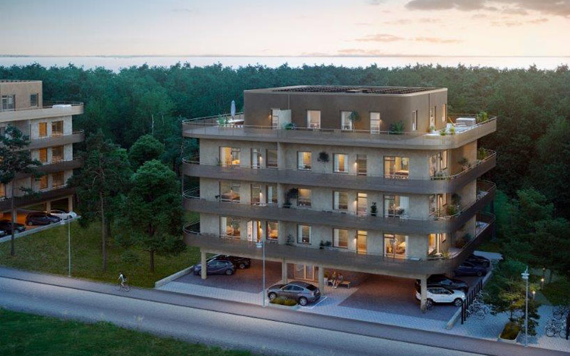 Lägenhetshus där några bilar syns parkerade på parkeringen under huskroppen